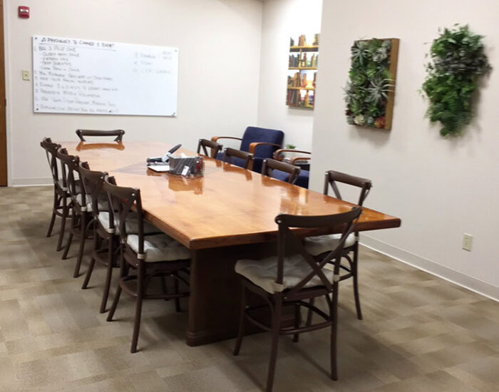 Modern conference room with wooden table and chairs, whiteboard, and decorative wall plants at Creve Coeur Behavioral Counseling center.