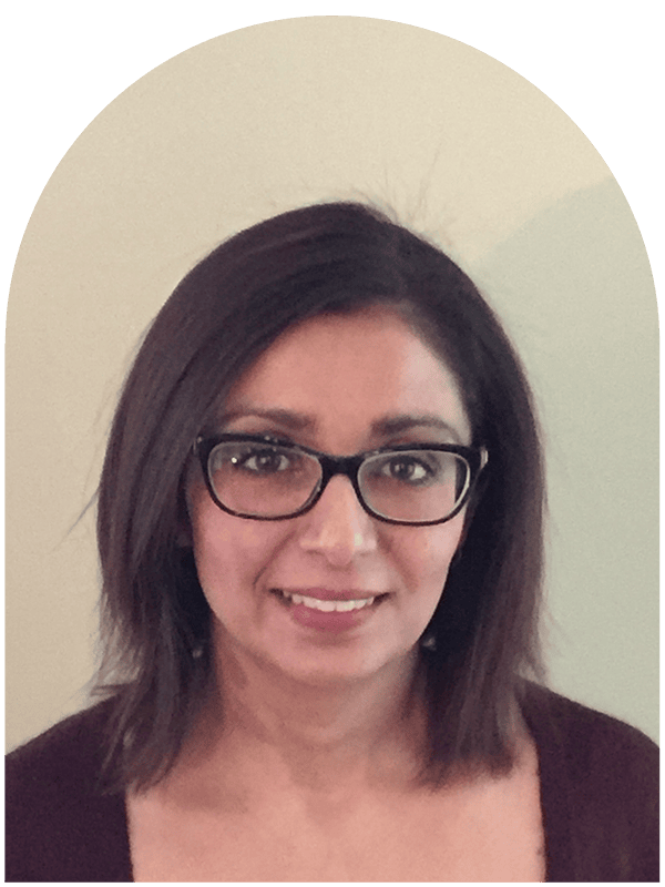 A smiling woman with shoulder-length dark hair and glasses, wearing a dark top, in front of a plain light-colored wall, representing Creve Coeur Behavioral Counseling, related to Sameera Malik.